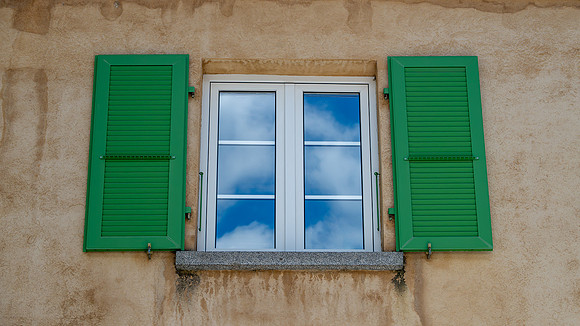 cloud reflection in windows with contrasting green shutters